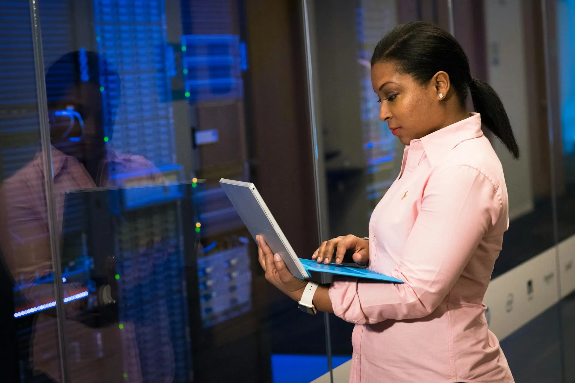 Professional woman using tablet in server room.